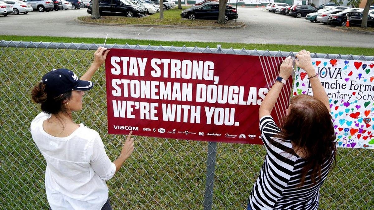 Volunteers hang banners around the perimeter of Marjory Stoneman High School in Parkland, Fla., to welcome back students who will be returning to school Wednesday two weeks after the mass shooting that killed 17 students and staff. (Susan Stocker/South Florida Sun-Sentinel via AP)