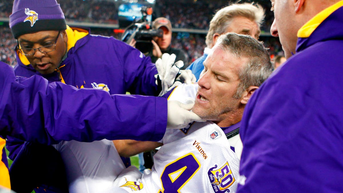 FILE - In this Oct. 31, 2010, file photo, Minnesota Vikings quarterback Brett Favre, center, is helped onto a cart to be taken off the field after a hit from New England Patriots' Myron Pryor during the fourth quarter of an NFL football game in Foxborough, Mass. Favre says he might have had 