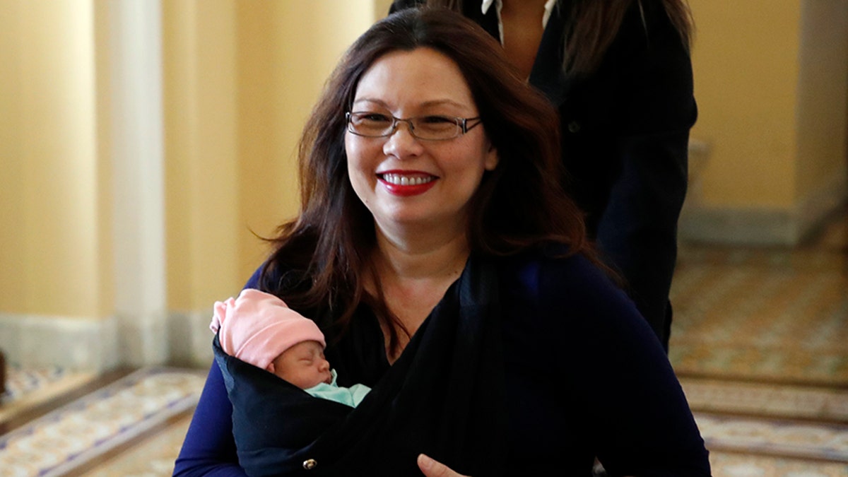 Sen. Tammy Duckworth, D-Ill., carries her baby Maile Pearl Bowlsbey after they went to the Senate floor to vote, on Capitol Hill, Thursday, April 19, 2018 in Washington. (AP Photo/Alex Brandon)