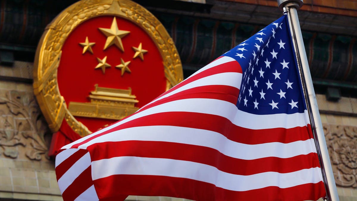 FILE - In this Nov. 9, 2017, file photo, an American flag is flown next to the Chinese national emblem during a welcome ceremony for visiting U.S. President Donald Trump outside the Great Hall of the People in Beijing. The State Department said an email notice Wednesday, May 23, 2018, that a U.S. government employee in southern China reported abnormal sensations of sound and pressure, recalling similar experiences among American diplomats in Cuba who later fell ill. (AP Photo/Andy Wong, File)