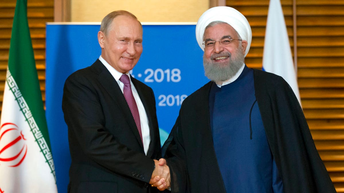 Russian President Vladimir Putin, left, shakes hands with Iranian President Hassan Rouhani during their meeting in Qingdao, China, Saturday, June 9, 2018. Rouhani said Russia and Iran should discuss the situation over the U.S. exit from the Iranian nuclear deal. (AP Photo/Alexander Zemlianichenko, Pool)