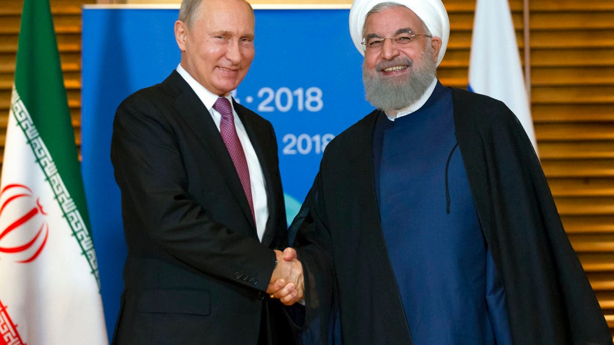 Russian President Vladimir Putin, left, shakes hands with Iranian President Hassan Rouhani during their meeting in Qingdao, China, Saturday, June 9, 2018. Rouhani said Russia and Iran should discuss the situation over the U.S. exit from the Iranian nuclear deal. (AP Photo/Alexander Zemlianichenko, Pool)