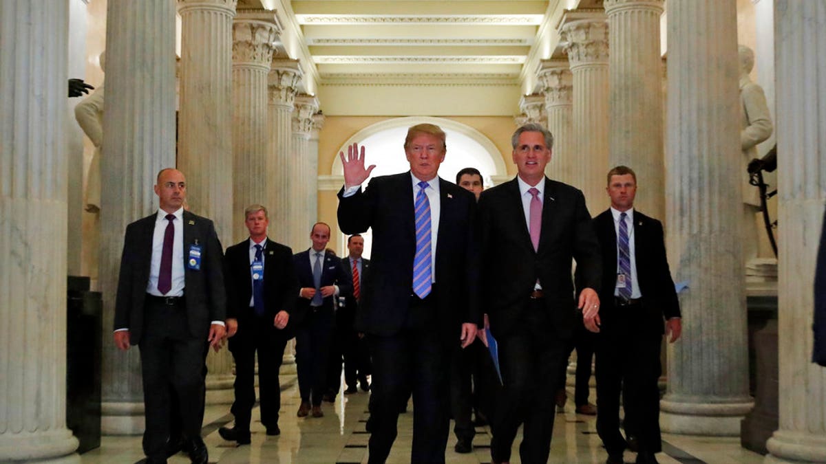 President Donald Trump, center, accompanied by House Majority Leader Kevin McCarthy of Calif., waves as he departs Capitol Hill in Washington, Tuesday, June 19, 2018, after a meeting to rally Republicans around a GOP immigration bill.  (AP Photo/Alex Brandon)