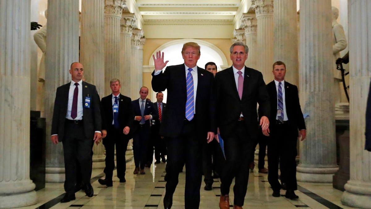 President Donald Trump, center, accompanied by House Majority Leader Kevin McCarthy of Calif., waves as he departs Capitol Hill in Washington, Tuesday, June 19, 2018, after a meeting to rally Republicans around a GOP immigration bill.  (AP Photo/Alex Brandon)