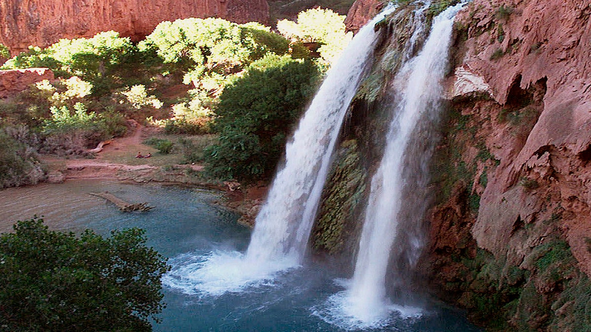 FILE - This 1997 file photo shows one of five waterfalls on Havasu Creek as its waters tumble 210 feet on the Havasupai Tribe's reservation in a southeastern branch of the Grand Canyon near Supai, Ariz. About 200 tourists are being evacuated from a campground on tribal land near famous waterfalls deep in a gorge off the Grand Canyon. Officials with the Havasupai Tribe say their reservation was hit with two rounds of flooding Wednesday, July 11, 2018, and early Thursday. (AP Photo/Bob Daugherty, File)