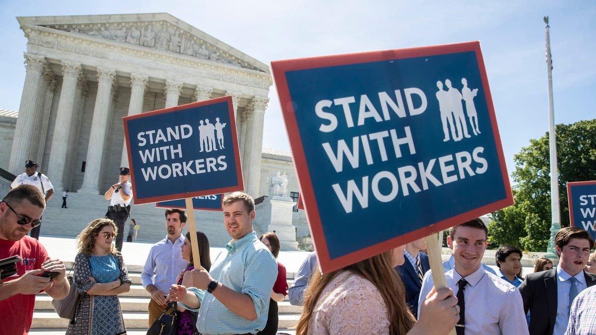 FILE - In this Monday, June 25, 2018 file photo, people gather at the Supreme Court awaiting a decision in an Illinois union dues case, Janus vs. AFSCME, in Washington. An Oregon state employee and a labor union have reached a settlement over her lawsuit seeking payback of obligatory union fees, marking the first refund of forced fees since the U.S. Supreme Court ruled in late June that government workers can't be required to contribute to labor groups, the employee's lawyers said Monday, July 30, 2018. (AP Photo/J. Scott Applewhite, File)