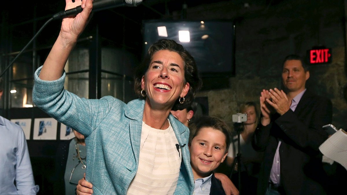 Incumbent Democratic Rhode Island Gov. Gina Raimondo waves to supporters alongside her son, Thompson, at her primary night victory party, Wednesday, Sept. 12, 2018, in Providence, R.I. (AP Photo/Elise Amendola)