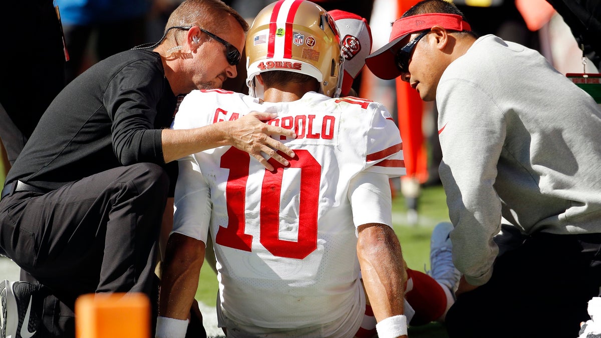 Trainers attend to San Francisco 49ers quarterback Jimmy Garoppolo (10) who was injured after a tackle by Kansas City Chiefs defensive back Steven Nelson during the second half of an NFL football game in Kansas City, Mo., Sunday, Sept. 23, 2018. (AP Photo/Charlie Riedel)