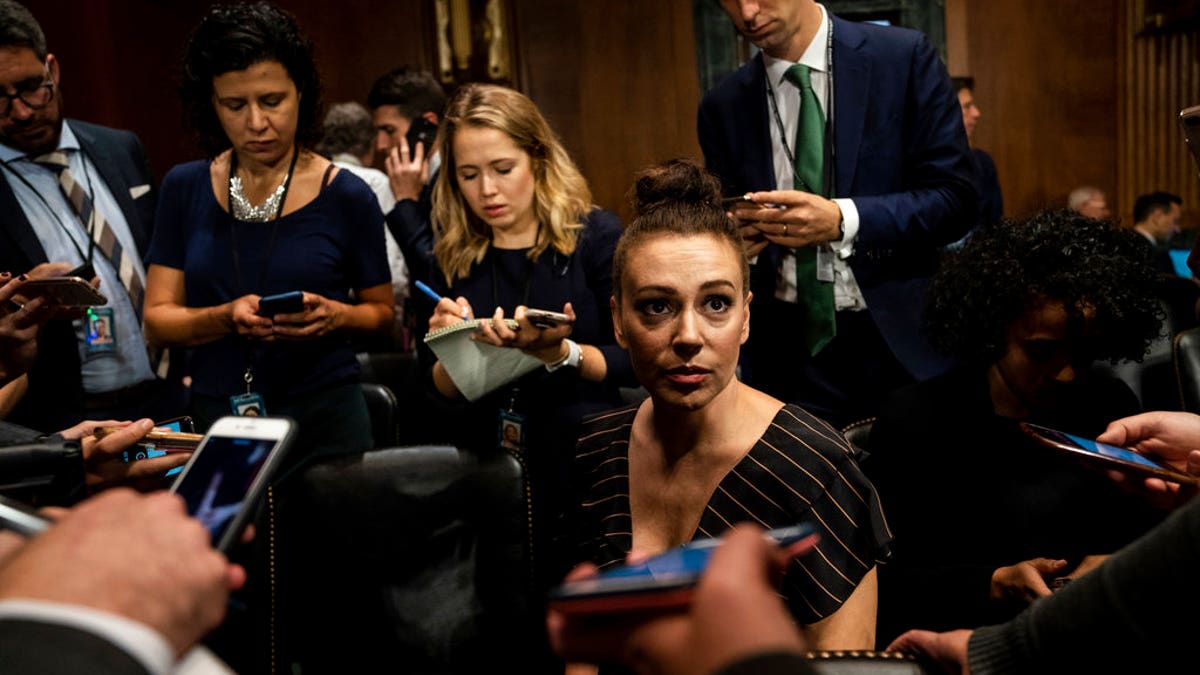 Actress Alyssa Milano is seen before a Senate Judiciary Committee hearing, Thursday, Sept. 27, 2018 on Capitol Hill in Washington with Christine Blasey Ford and Supreme Court nominee Brett Kavanaugh. (Erin Schaff/The New York Times via AP, Pool)