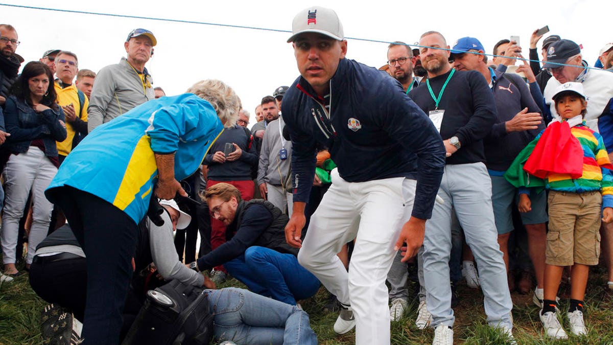 Brooks Koepka of the US gives a dedicated golf glove to spectator he wounded when his ball hit her on the 6th hole during his fourball match on the opening day of the 42nd Ryder Cup at Le Golf National in Saint-Quentin-en-Yvelines, outside Paris, France, Friday, Sept. 28, 2018. (AP Photo/Francois Mori)