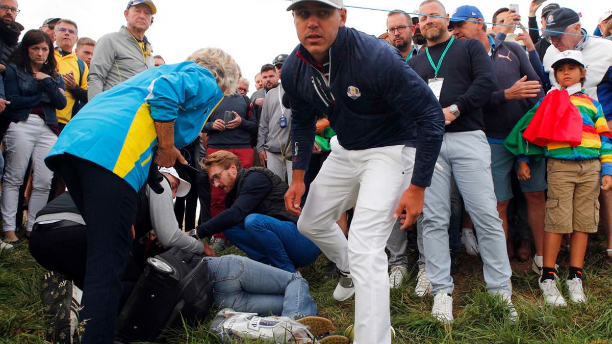Brooks Koepka of the US gives a dedicated golf glove to spectator he wounded when his ball hit her on the 6th hole during his fourball match on the opening day of the 42nd Ryder Cup at Le Golf National in Saint-Quentin-en-Yvelines, outside Paris, France, Friday, Sept. 28, 2018. (AP Photo/Francois Mori)