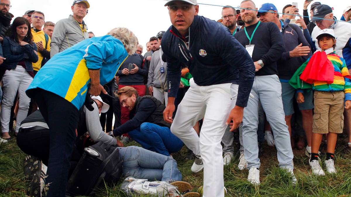 Brooks Koepka of the US gives a dedicated golf glove to spectator he wounded when his ball hit her on the 6th hole during his fourball match on the opening day of the 42nd Ryder Cup at Le Golf National in Saint-Quentin-en-Yvelines, outside Paris, France, Friday, Sept. 28, 2018. (AP Photo/Francois Mori)