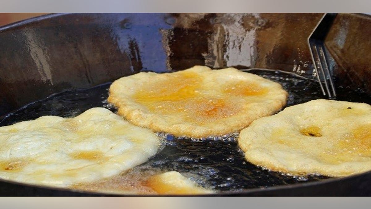 tasty Fried Apple fritters in the cauldron of boiling oil on sale