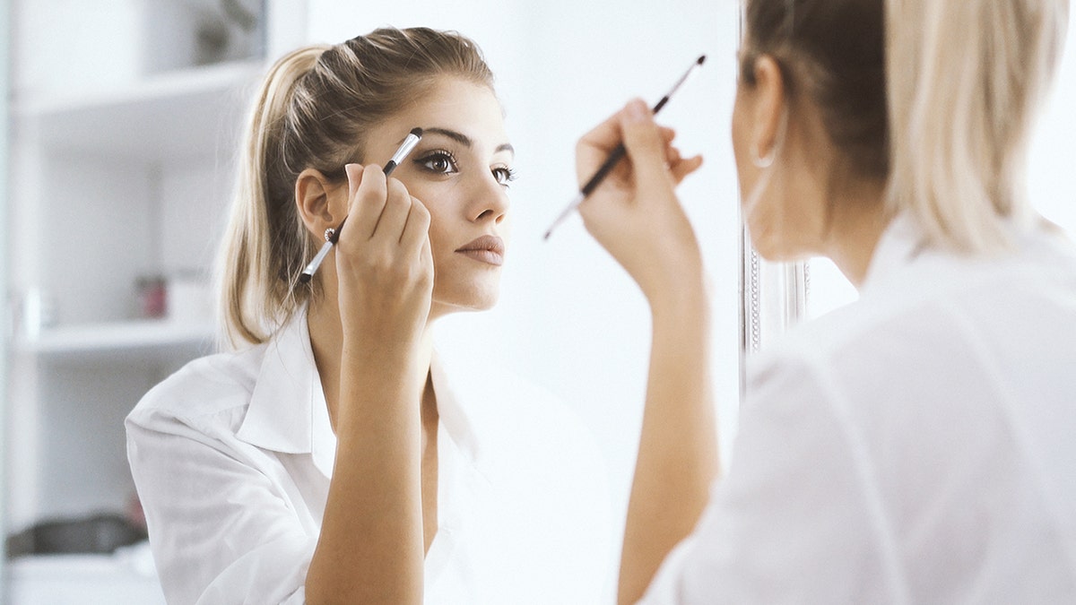 woman applies makeup