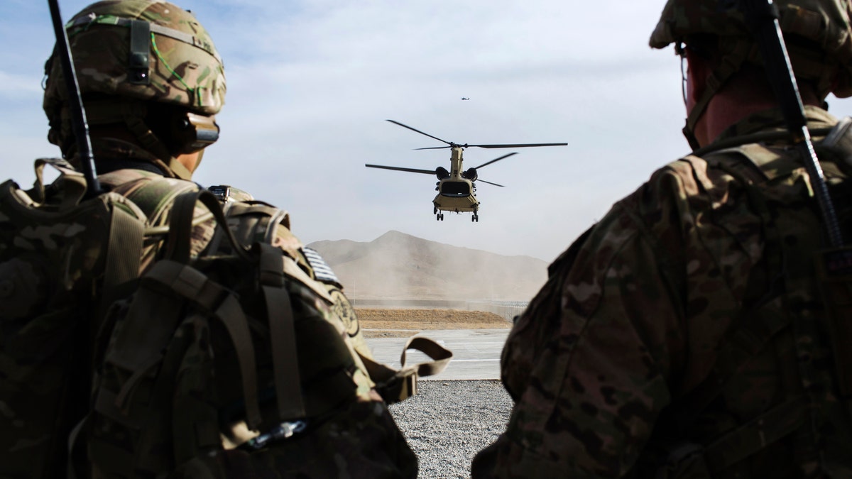 U.S. soldiers from the 3rd Cavalry Regiment watch as CH-47 Chinook helicopter from the 82nd Combat Aviation Brigade lands after an advising mission at the Afghan National Army headquarters for the 203rd Corps in the Paktia province of Afghanistan December 21, 2014. REUTERS/Lucas Jackson (AFGHANISTAN - Tags: CIVIL UNREST POLITICS MILITARY) - RTR4IUN9