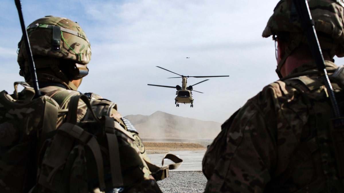 U.S. soldiers from the 3rd Cavalry Regiment watch as CH-47 Chinook helicopter from the 82nd Combat Aviation Brigade lands after an advising mission at the Afghan National Army headquarters for the 203rd Corps in the Paktia province of Afghanistan December 21, 2014. REUTERS/Lucas Jackson (AFGHANISTAN - Tags: CIVIL UNREST POLITICS MILITARY) - RTR4IUN9