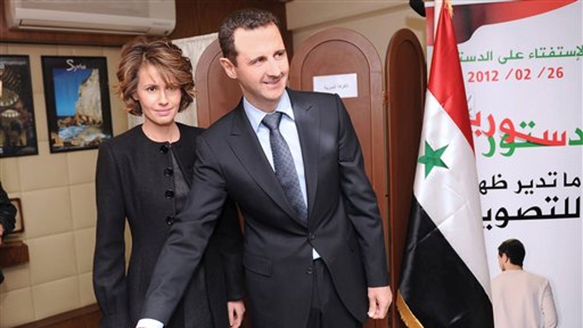 Feb. 26, 2012: In this photo released by the Syrian official news agency SANA, Syrian President Bashar Assad casts his ballot next to his wife Asma at a polling station during a referendum on the new constitution, in Damascus, Syria. 