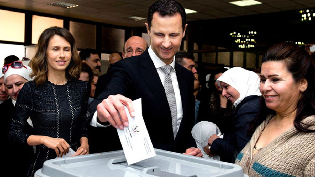 This photo released on the official Facebook page of Syrian Presidency, shows Syrian President Bashar Assad casting his ballot in the parliamentary elections, as his wife Asma, left, is standing next to him, in Damascus, Syria, Wednesday, April 13, 2016. Syrians living in government-held areas are to vote Wednesday in parliamentary elections, hours ahead of the resumption of talks in Geneva to resolve the country's five-year-long civil war. (Syrian Presidency via AP)