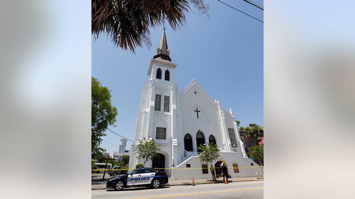 FILE- In this June 18, 2015 file photo, two Charleston police officers stand in front of the Emanuel AME Church in Charleston, S.C. The trial for Dylann Roof, a white man accused of killing nine black people at the church, started Wednesday, Dec. 7, 2016, at the federal courthouse in Charleston, SC. (AP Photo/Stephen B. Morton, File)