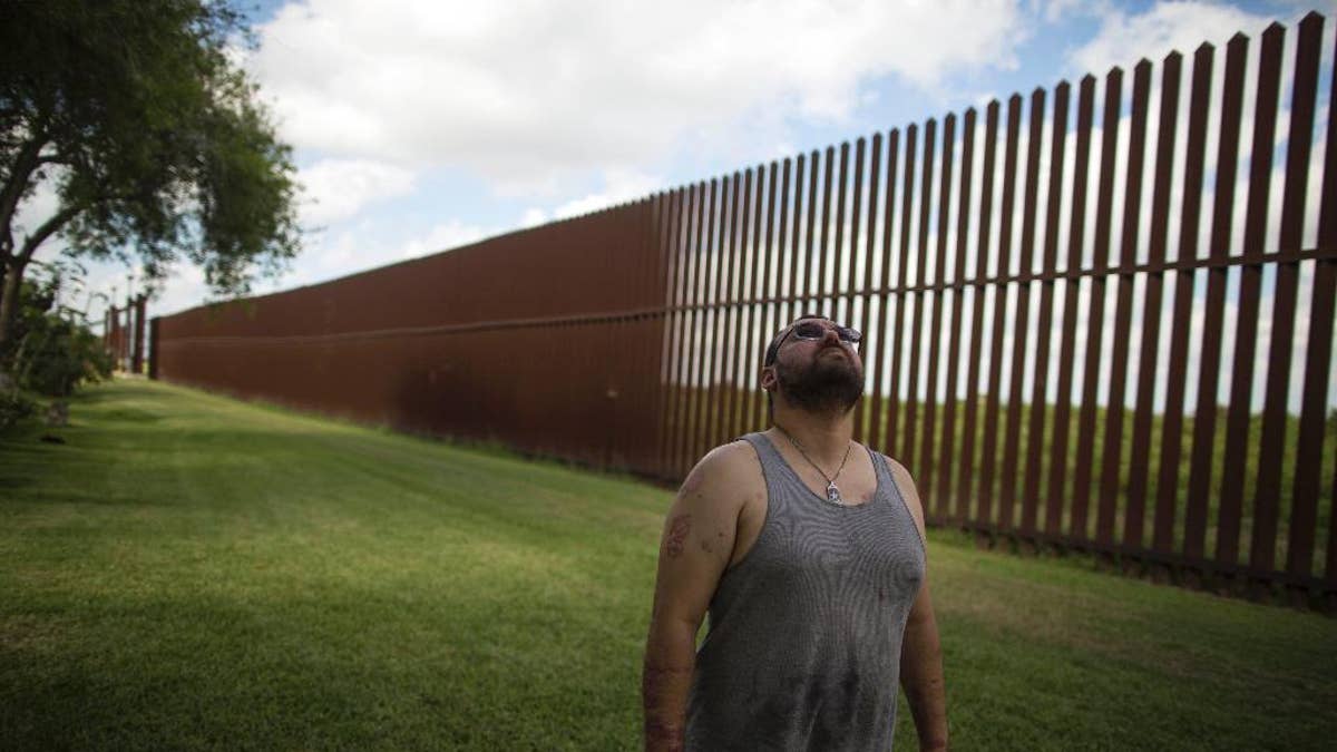 FILE - In this March 22, 2017, file photo, Antonio Reyes of Brownsville, Texas, stands by the U.S.-Mexico border fence near his home. Reyes said he's seen people scale the border fence that bisects his backyard and jump down in seconds. Sometimes they carry bales of what appear to be drugs. A higher wall is 