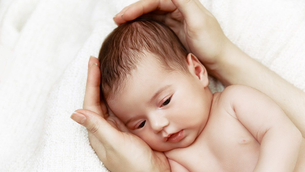 Cute newborn baby lying in mother's hands