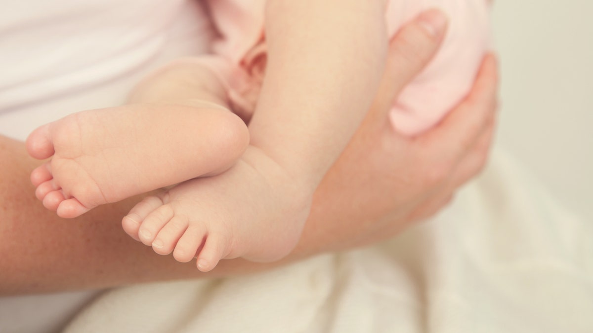 Baby Feet of baby girl being held by mother