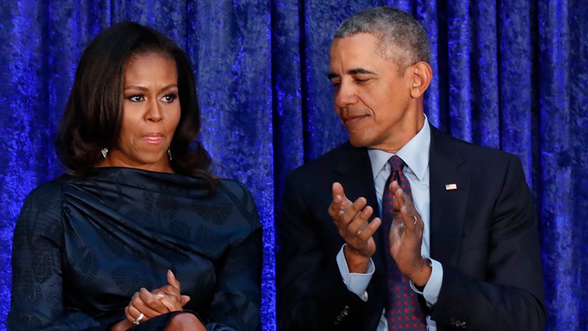 Former U.S. President Barack Obama sits with former first lady Michelle Obama applaud during the unveiling of their portraits at the Smithsonianâs National Portrait Gallery in Washington, U.S., February 12, 2018. REUTERS/Jim Bourg - HP1EE2C18GF0E