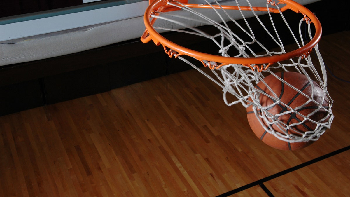 A basketball going through a hoop and net. The hardwood floor can be seen below.Here is a good link to some other