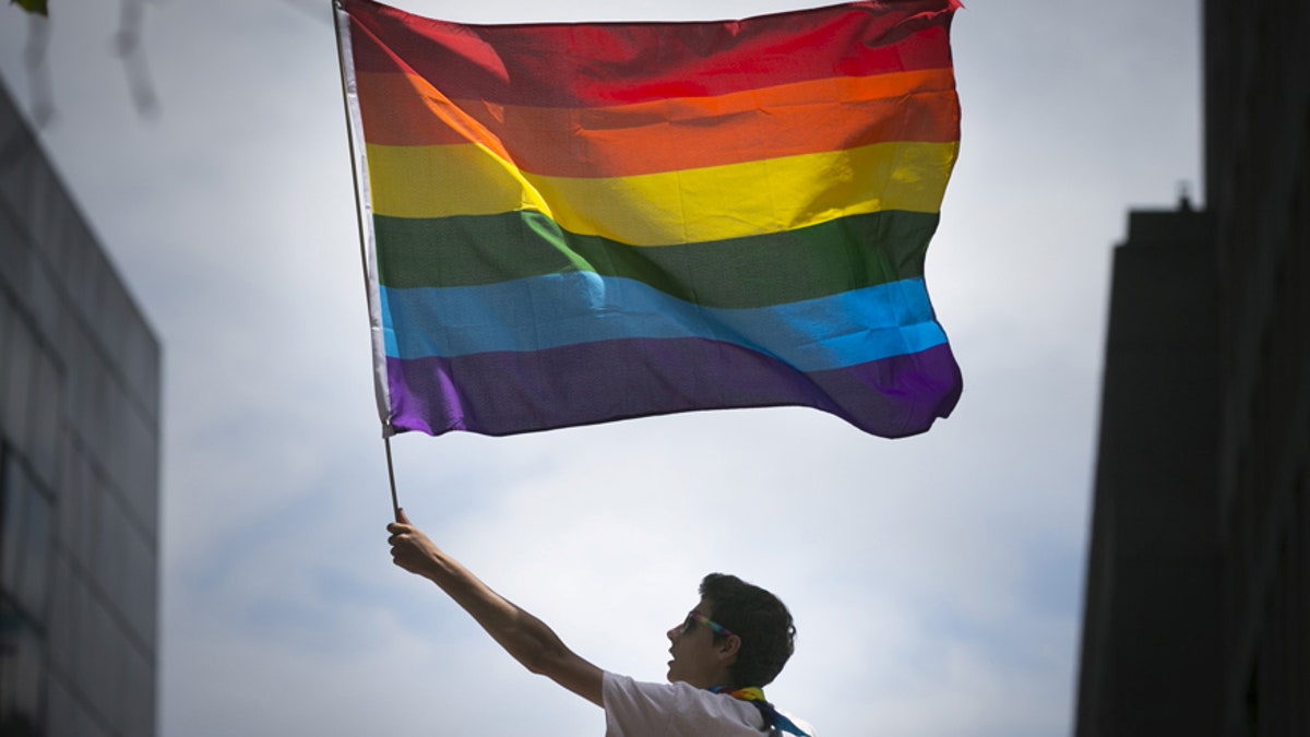 June 28, 2015: A man waves a rainbow flag while observing a gay pride parade in San Francisco, Calif.