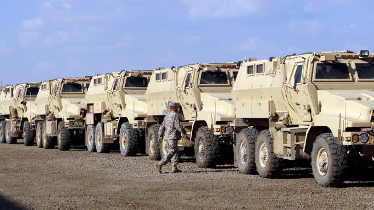 U.S. army soldiers walks past military armored vehicles are ready to be shipped out of Iraq at Camp Victory Complex that is set to close in Baghdad, Iraq, Monday, Nov. 7, 2011. The U.S. has promised to withdraw from Iraq by the end of the year as required by a 2008 security agreement between Washington and Baghdad. Some 39,000 U.S. troops are scheduled to clear out along with their equipment. (AP Photo/Khalid Mohammed)