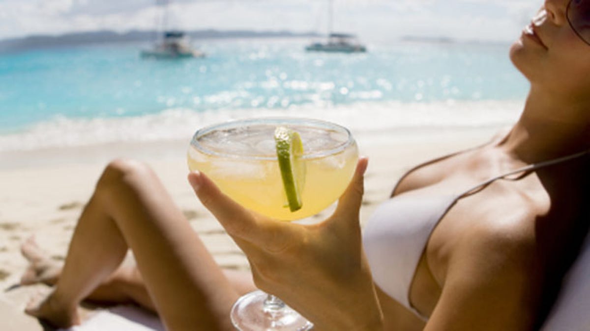 be95f220-woman relaxing at the beach drinking margarita cocktail