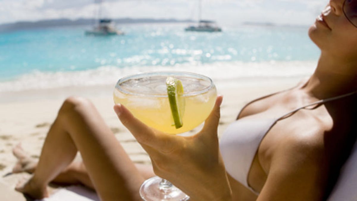 be95f220-woman relaxing at the beach drinking margarita cocktail