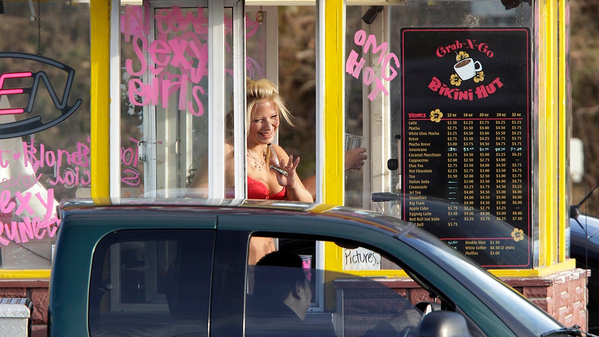 A barista at a Grab-N-Go Bikini Hut espresso stand holds money as she waves to a customer, Tuesday, Feb. 2, 2010, just outside the city limits of Everett, Wash., in Snohomish County. Coffee shops in the Seattle area introduced the world to 