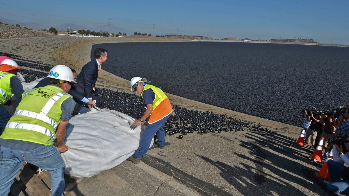 Los Angeles City Councilman Mitch Englander, Mayor Eric Garcetti (wearing a yellow tie) and LADWP workers deposit the final installment of 96 million shade balls into the Los Angeles Reservoir. (Art Mochizuki, LADWP)