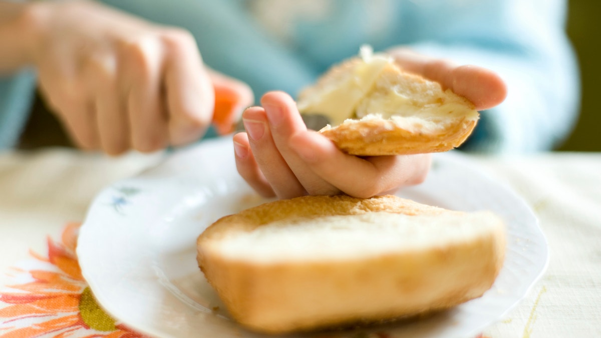 Breakfast close-up with hands, bread and butter