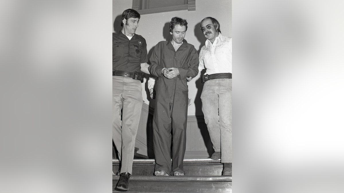 In this 1977 photo serial killer Ted Bundy, center, is escorted out of court in Pitkin County, Colo. The Glenwood Springs Post-Independent discovered the 40-year-old photo of Bundy, along with others, that had been locked in an old safe in the newsroom, which a local locksmith volunteered to open. The photos show Bundy in custody in 1977, the year he escaped from local law enforcement twice while awaiting a murder trial.  (Glenwood Springs Post Independent via AP)