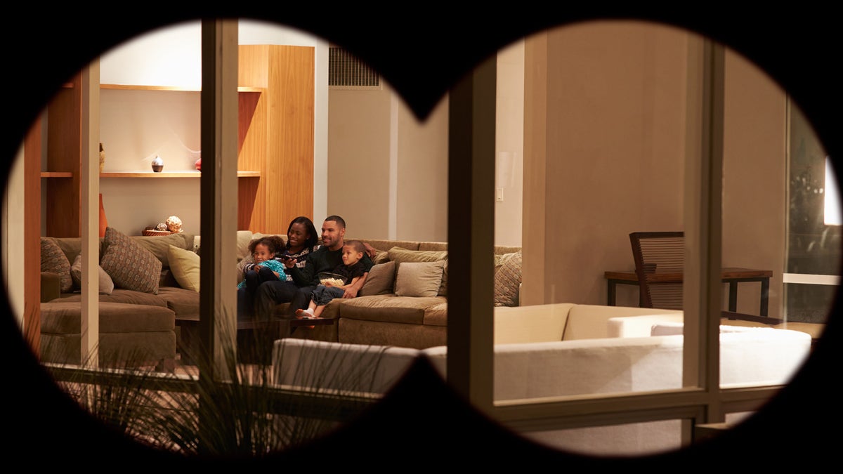 Family Watching TV At Home Viewed From Outside