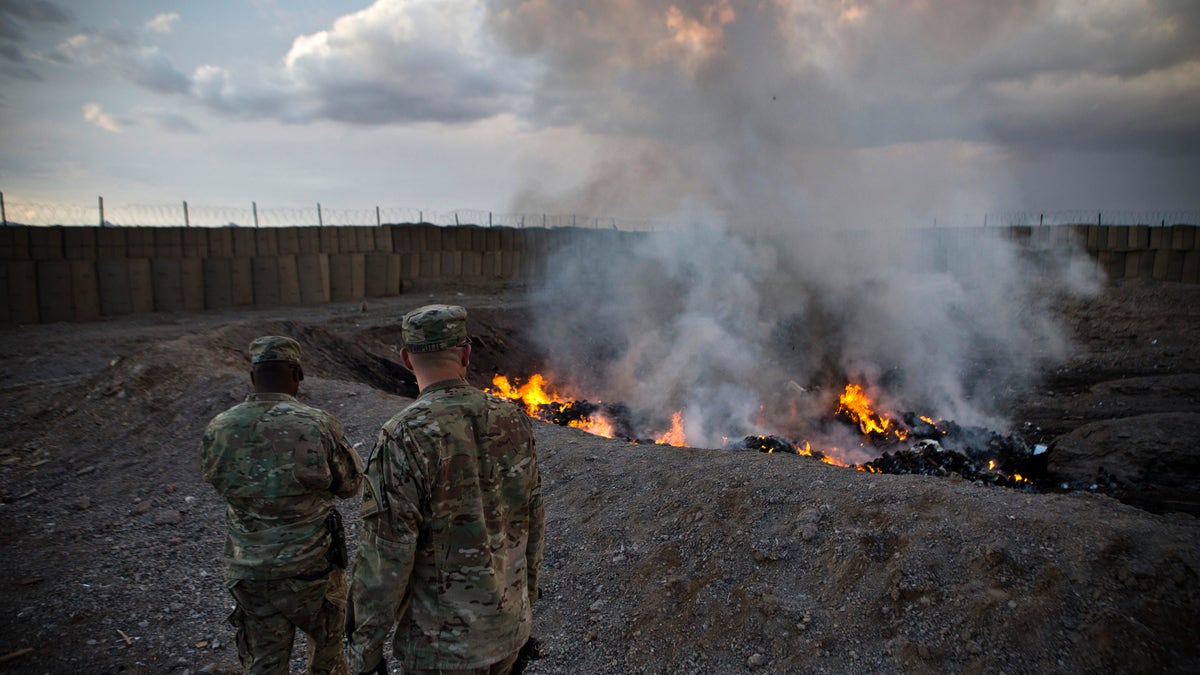 U.S. Army soldiers watch garbage burn in a burn-pit at Forward Operating Base Azzizulah in Maiwand District, Kandahar Province, Afghanistan, February 4, 2013. REUTERS/Andrew Burton (AFGHANISTAN - Tags: MILITARY) - RTR3DCLD