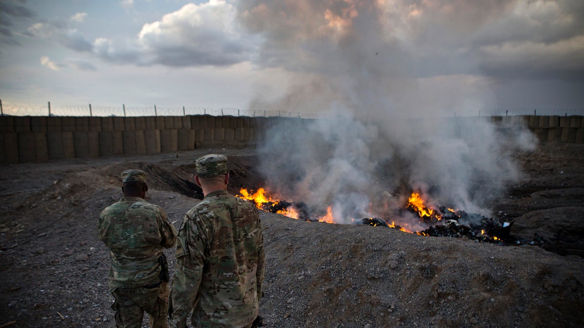 U.S. Army soldiers watch garbage burn in a burn-pit at Forward Operating Base Azzizulah in Maiwand District, Kandahar Province, Afghanistan, February 4, 2013. REUTERS/Andrew Burton (AFGHANISTAN - Tags: MILITARY) - RTR3DCLD