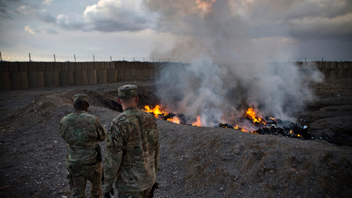 February 4, 2013: U.S. Army soldiers watch garbage burn in a burn-pit at Forward Operating Base Azzizulah in the Kandahar Province of Afghanistan.