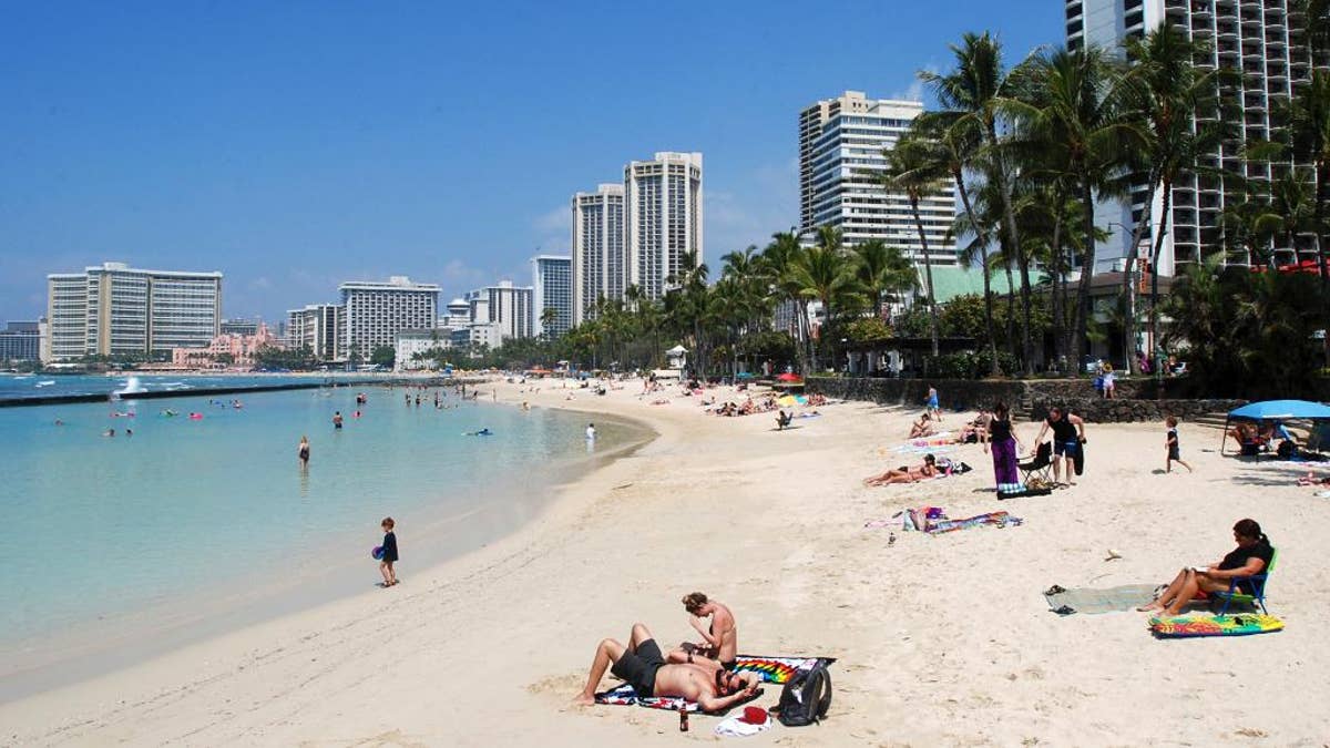 FILE - In this Monday, March 13, 2017 file photo, people relax on the beach in Waikiki in Honolulu. A federal judge in Hawaii is hearing arguments on whether to extend his temporary order blocking President Donald Trump’s revised travel ban. A hearing in Honolulu is set for Wednesday, March 29, 2017. 