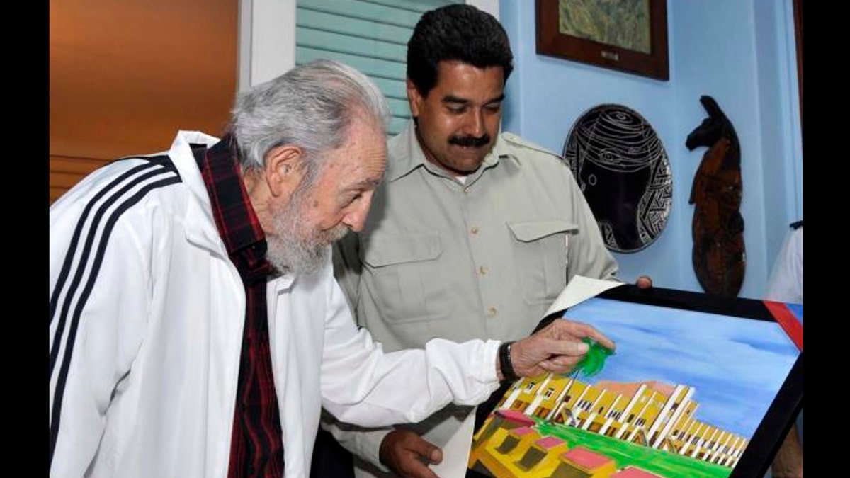 In this photo released by Miraflores Press Office through the twitter account of Information Minister Ernesto Villegas, Venezuela's President Nicolas Maduro, right, speaks with Cuba's former President Fidel Castro about a picture painted by former Venezuela President Hiugo chavez during their meeting at Havana, Cuba, on Saturday, July 27, 2013. (AP Photo/Miraflores Press Office)