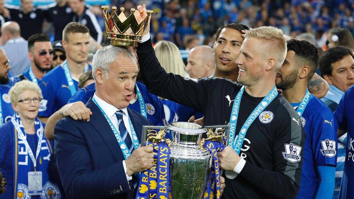 FILE - In this Saturday, May 7, 2016 file photo Leicester City team manager Claudio Ranieri has the crown of the trophy placed on his head by Leicester goalkeeper Kasper Schmeichel as they celebrate becoming the English Premier League soccer champions at King Power stadium in Leicester, England. Leicester City announced Thursday, Feb. 23, 2017 that they have sacked manager Claudio Ranieri less than a year after their incredible run to the Premier League title. (AP Photo/Matt Dunham, File)