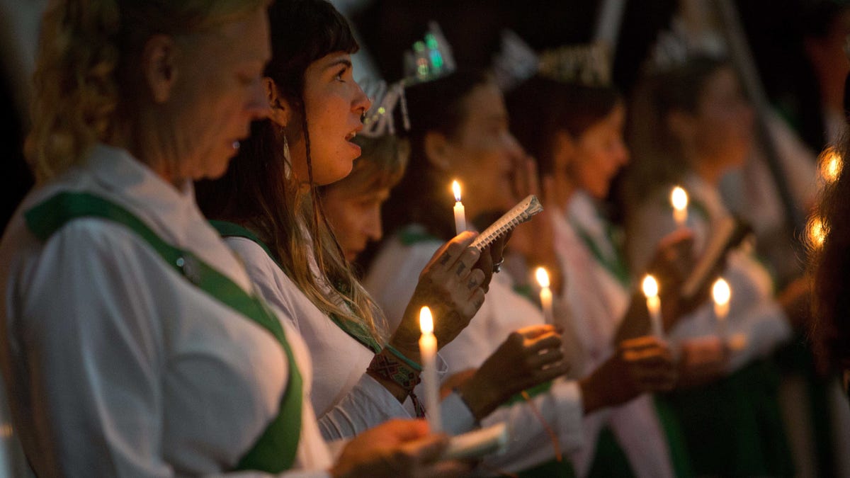 In this June 22, 2016 photo, women hold candles during a religious service in the church of the doctrine of Holy Daime, in Ceu do Mapia, Amazonas state, Brazil. At the church men and women line up in two separate rows to drink the tea after making the sign of the cross. They then sing together prayers and psalms in a large circle. (AP Photo/Eraldo Peres)