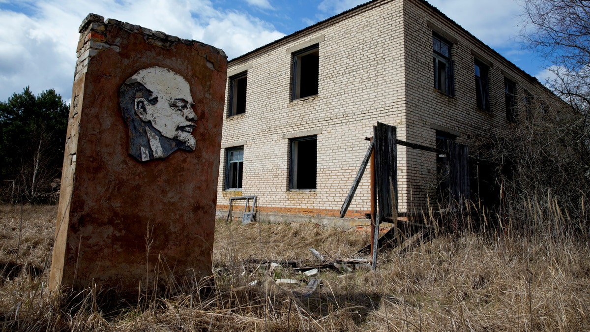 A panel with a portrait of Soviet state founder Vladimir Lenin and an abandoned building are seen at the 30 km (19 miles) exclusion zone around the Chernobyl nuclear reactor in the abandoned village of Orevichi, Belarus, March 12, 2016. REUTERS/Vasily Fedosenko        SEARCH 