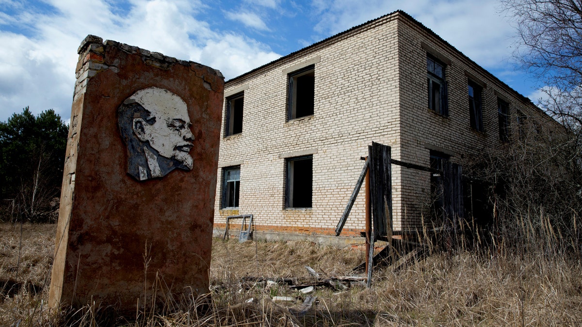 A panel with a portrait of Soviet state founder Vladimir Lenin and an abandoned building are seen at the 30 km (19 miles) exclusion zone around the Chernobyl nuclear reactor in the abandoned village of Orevichi, Belarus, March 12, 2016. REUTERS/Vasily Fedosenko        SEARCH 