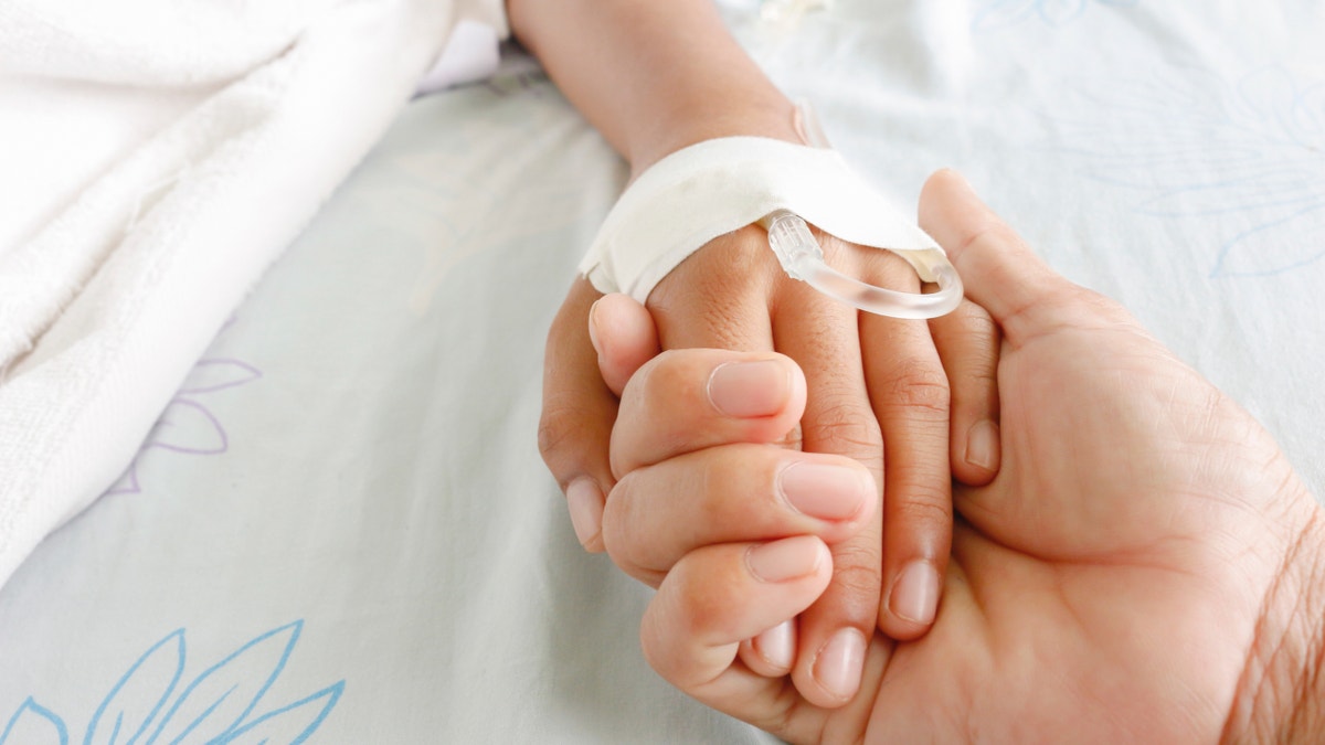 Mother and child hold hands in a medical setting.