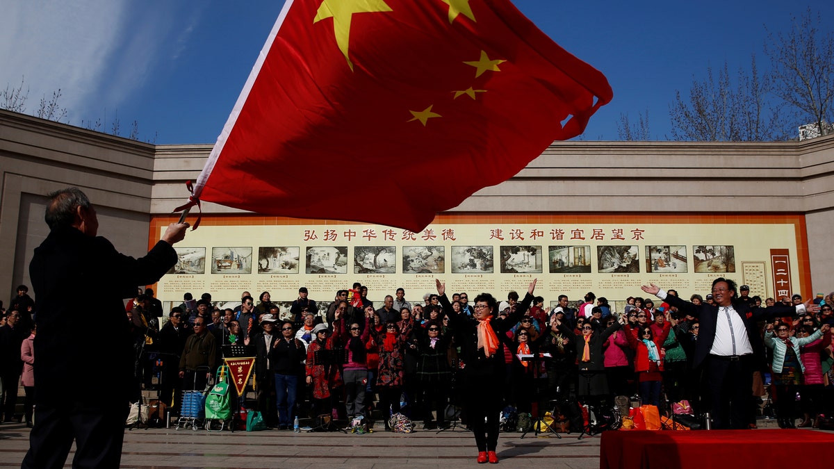 A man waves the Chinese national flag as an amateur choir performs in a park in a residential neighbourhood in Beijing, China February 28, 2017. REUTERS/Thomas Peter - RTS10PYV
