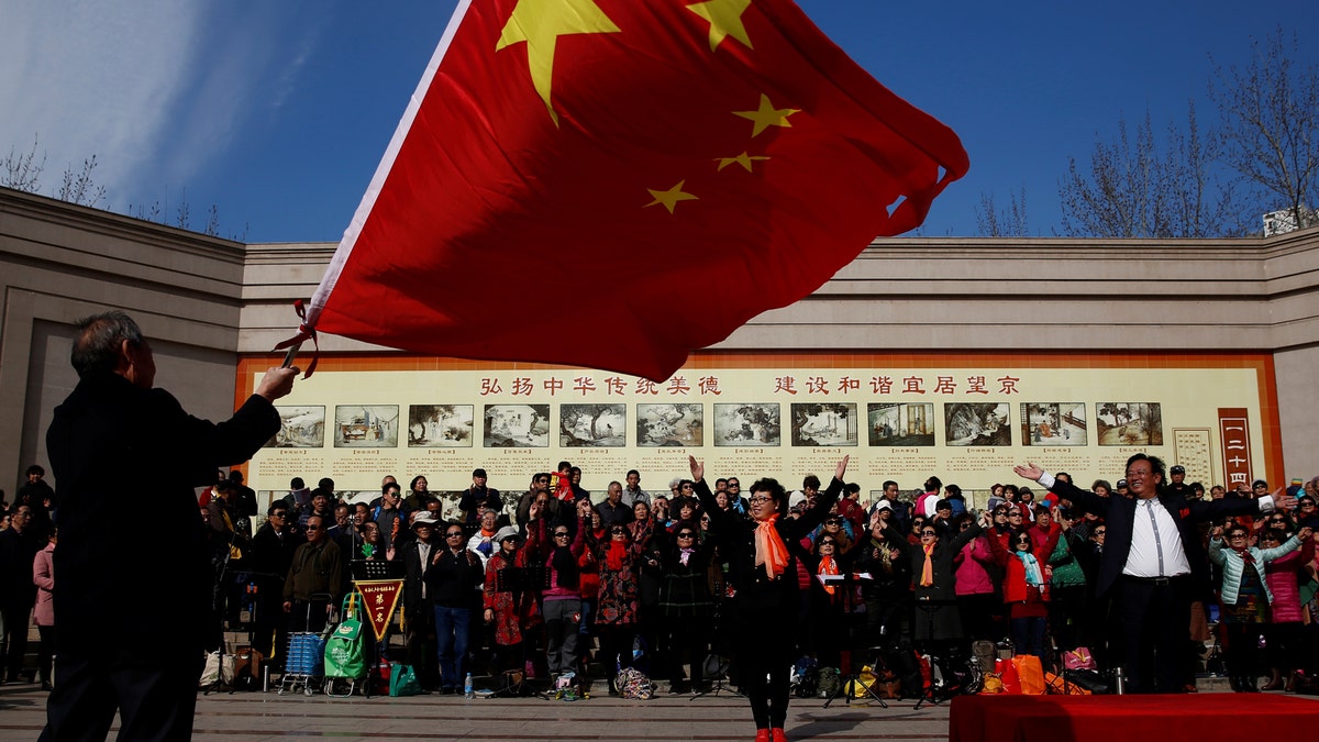 A man waves the Chinese national flag as an amateur choir performs in a park in a residential neighbourhood in Beijing, China February 28, 2017. REUTERS/Thomas Peter - RTS10PYV