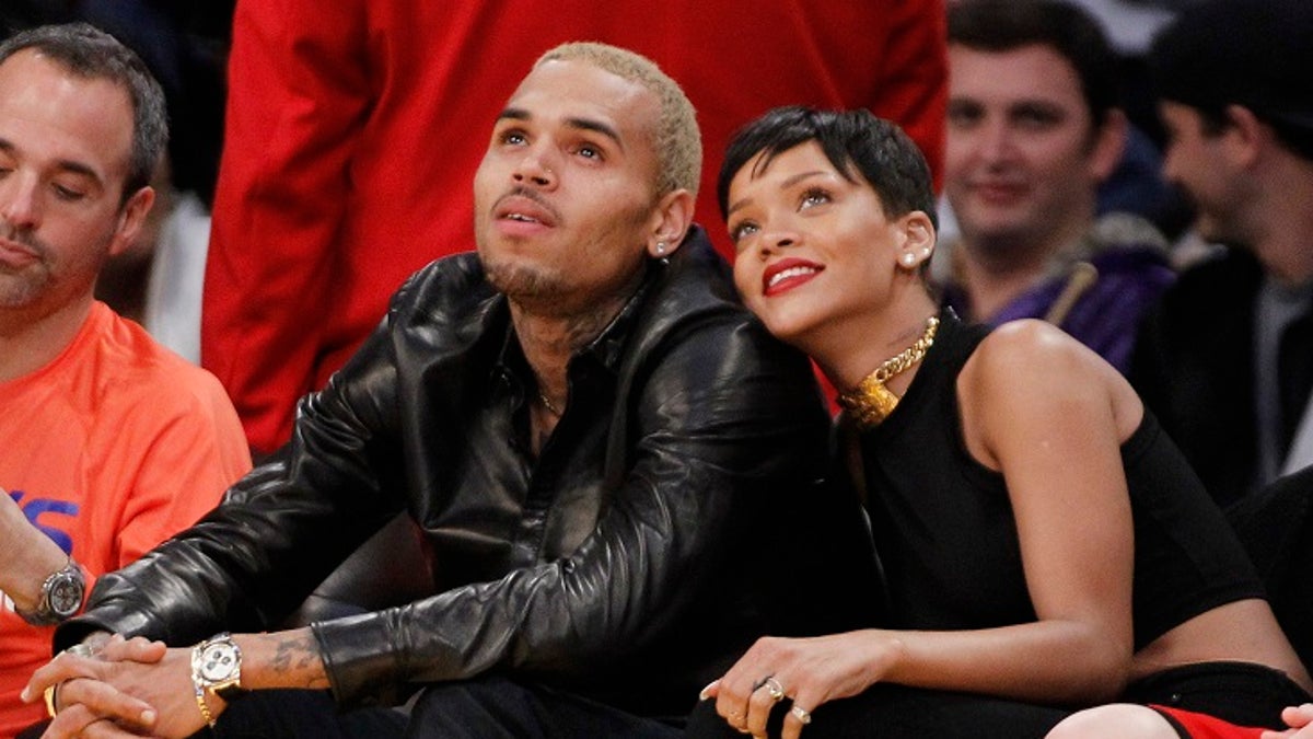 Recording artist Rihanna (R) leans her head on Chris Brown as they sit together at the NBA basketball game between the New York Knicks and Los Angeles Lakers in Los Angeles December 25, 2012. REUTERS/Danny Moloshok (UNITED STATES - Tags: SPORT BASKETBALL ENTERTAINMENT) - RTR3BWFP